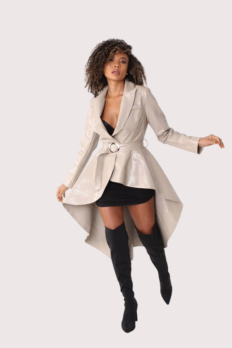 Beige high-low belted coat turning pose showing asymmetrical hem – For Her NYC