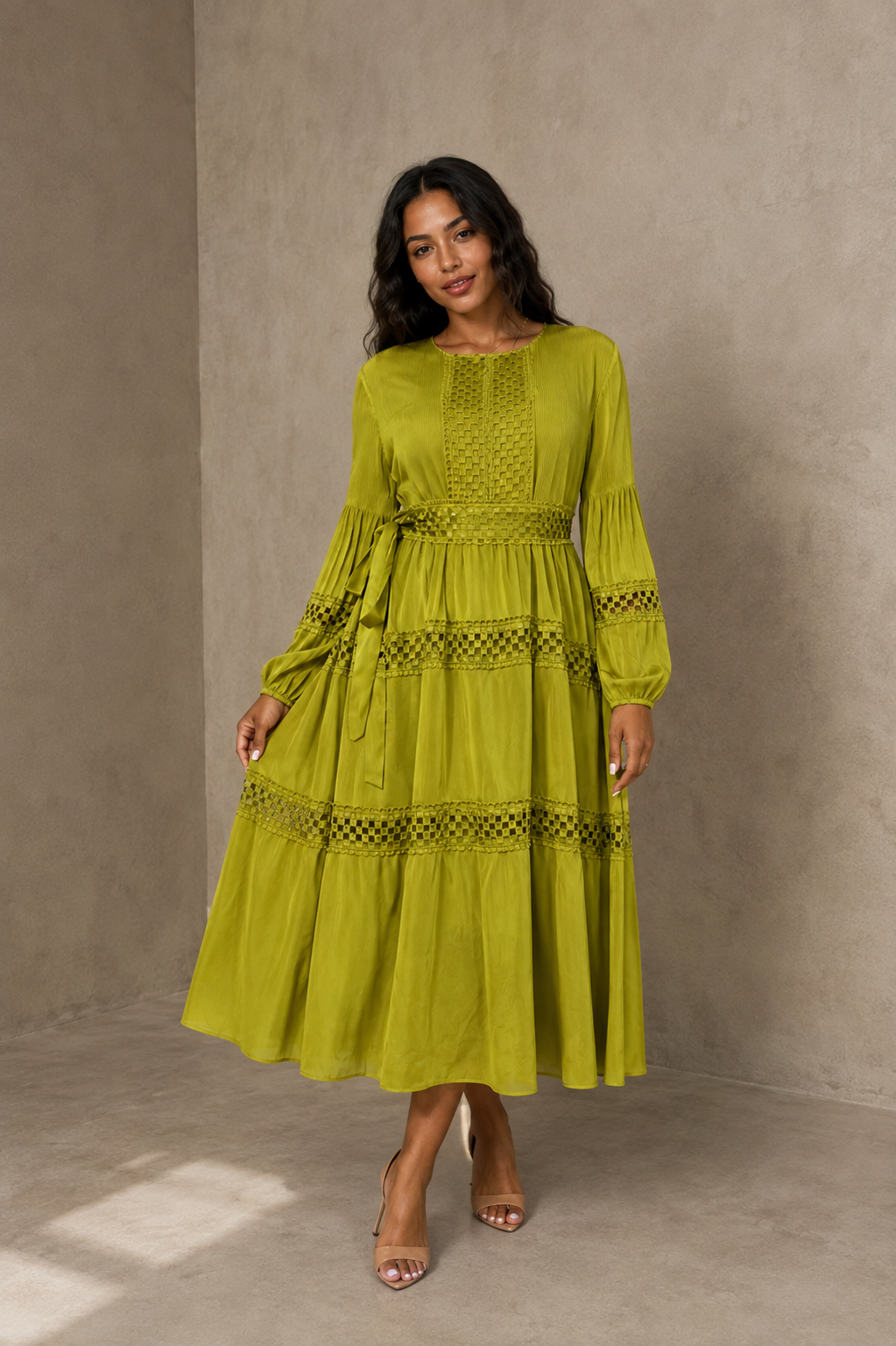 Front view of model wearing a green long sleeve tiered midi dress with lace trim and flowing layered skirt, For Her NYC