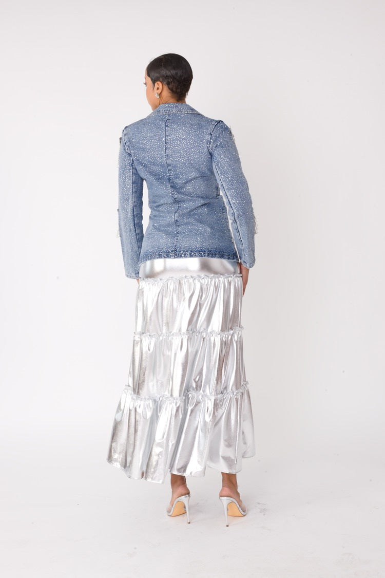 Model wearing the fringe-cropped-denim_jacket with silver metallic tiered maxi skirt standing back facing, showcasing lustrous finish and dramatic tiered silhouette by For Her NYC