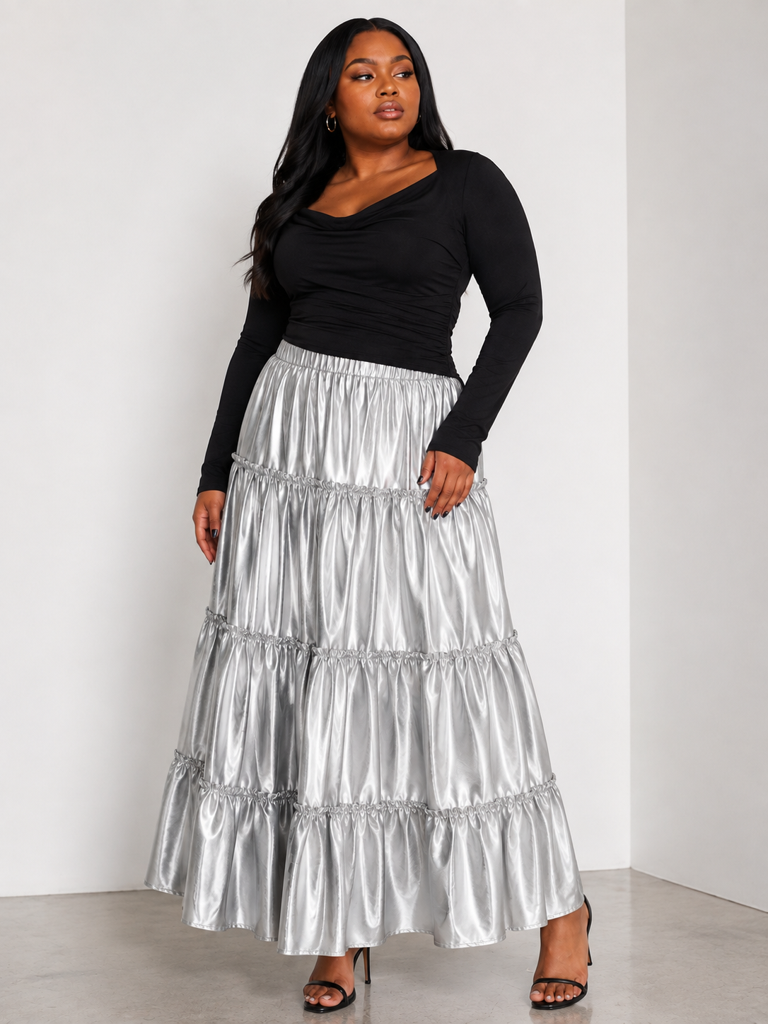 Model wearing the silver metallic tiered maxi skirt standing front facing, showcasing lustrous finish and dramatic tiered silhouette by For Her NYC