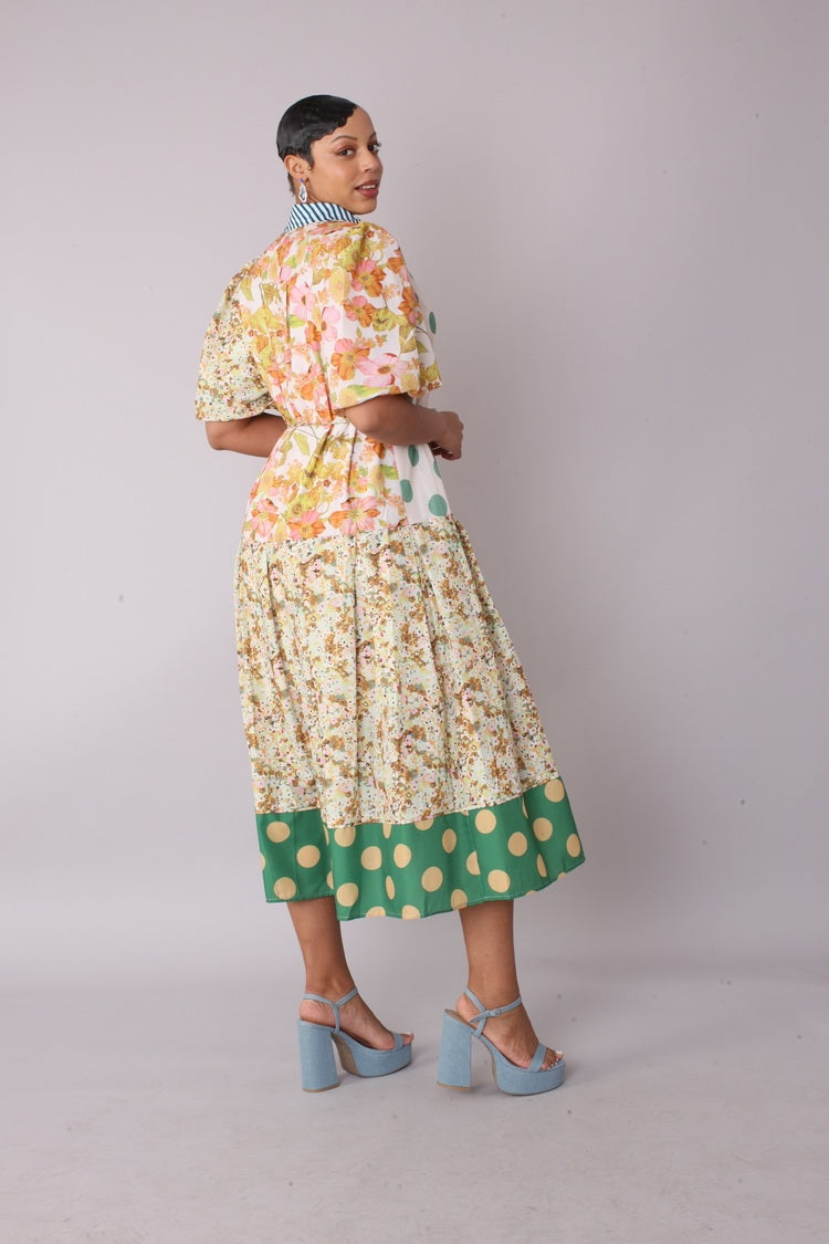 Three quarter angled view of model wearing the multi print mixed print midi dress emphasizing artistic pattern placement and flowing midi silhouette by For Her NYC