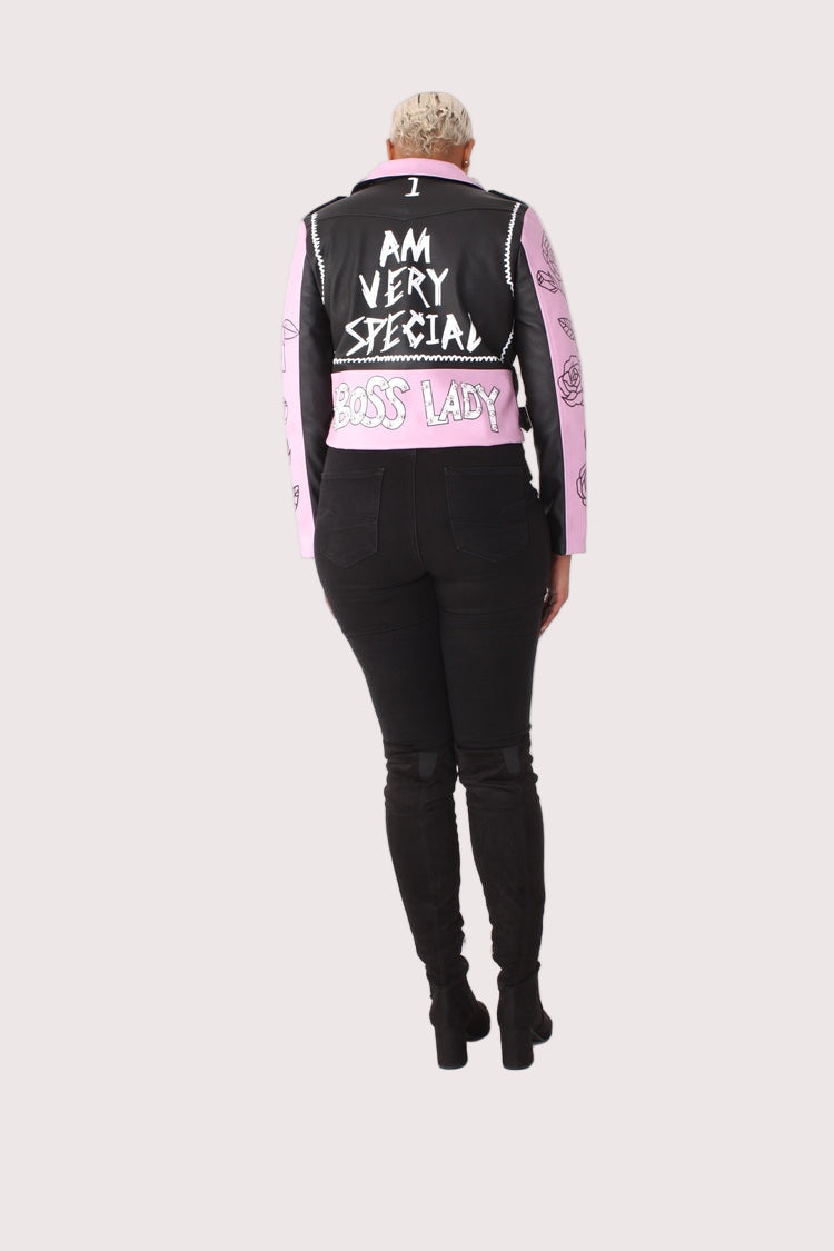 Model wearing multicolor faux leather jacket with pins and studs, full back view highlighting positive message graphic on back by For Her NYC