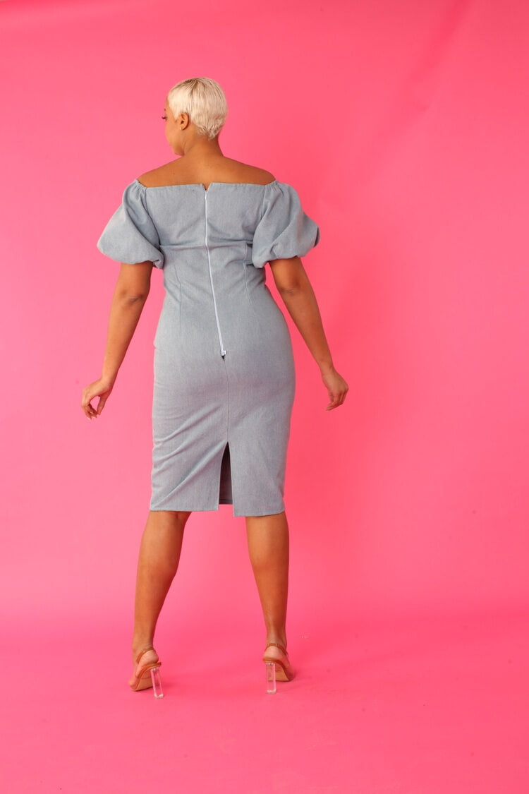 Back view of model wearing a blue off-shoulder denim pencil dress with puff sleeves — For Her NYC.