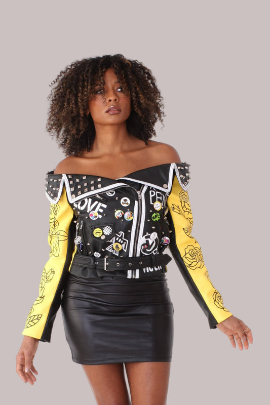 Front: Off-the-shoulder graffiti faux leather jacket in black and yellow, front view, For Her NYC.