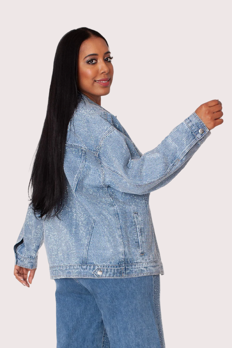 Side angle view of oversized rhinestone denim jacket with long sleeves and shimmering rhinestone detailing.