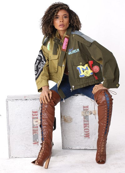 Army green patchwork utility woven jacket with mixed patch detailing and soft woven fabric, seated lifestyle view by For Her NYC