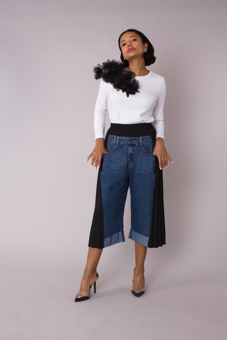 Model wearing Pleated Panel Denim Culottes in walking forward pose highlighting movement and structured pleated design, For Her NYC