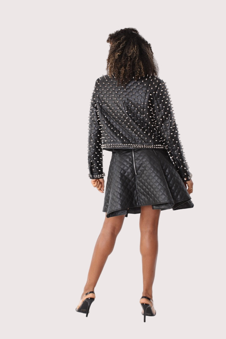 Model wearing pleather quilted flared skirt with studs in black, back view highlighting skirt shape, stud placement, and clean hemline by For Her NYC