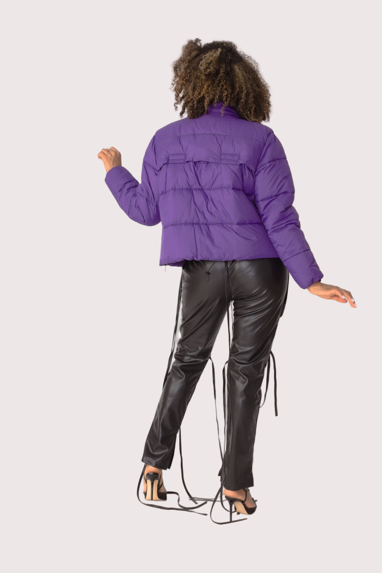Model wearing purple plush puffer jacket, back view highlighting padded construction, oversized fit, and full faux fur texture by For Her NYC