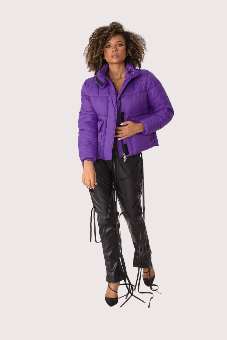 Model wearing purple plush puffer jacket, front walking pose showcasing casual movement, padded warmth, and statement color by For Her NYC