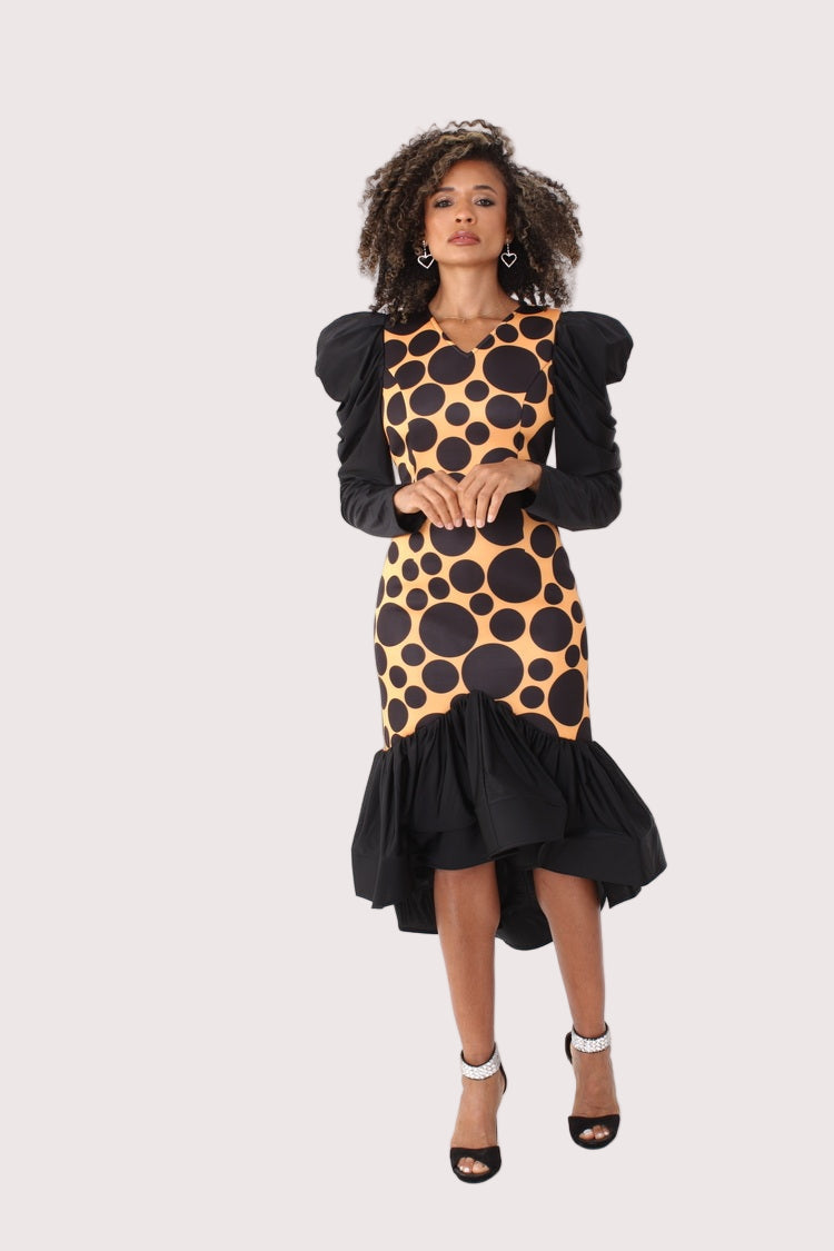 Black and mustard polka dot high-low dress with puff sleeves shown from the front in a full-length standing pose, highlighting the fitted bodice and dramatic ruffle hem, special occasion dress by For Her NYC