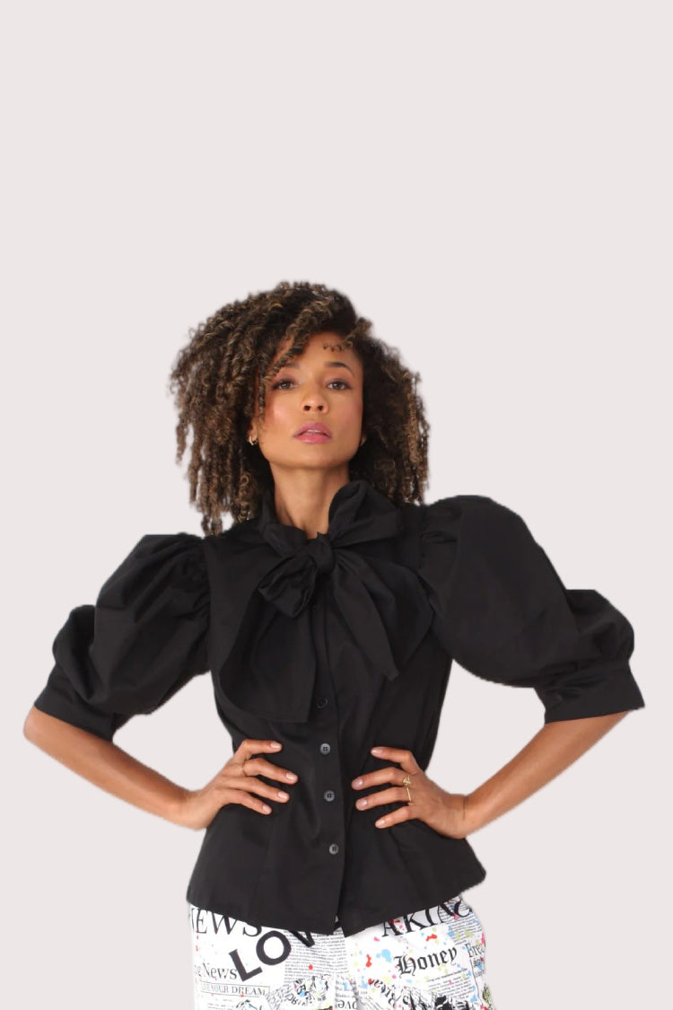 Model wearing black puff sleeve tie neck blouse with bow detail and structured silhouette, chic statement top styling, For Her NYC