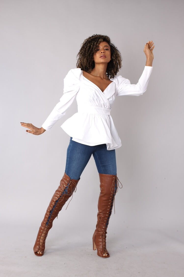 Angled standing view of white puff sleeve wrap peplum top with hand out – For Her NYC