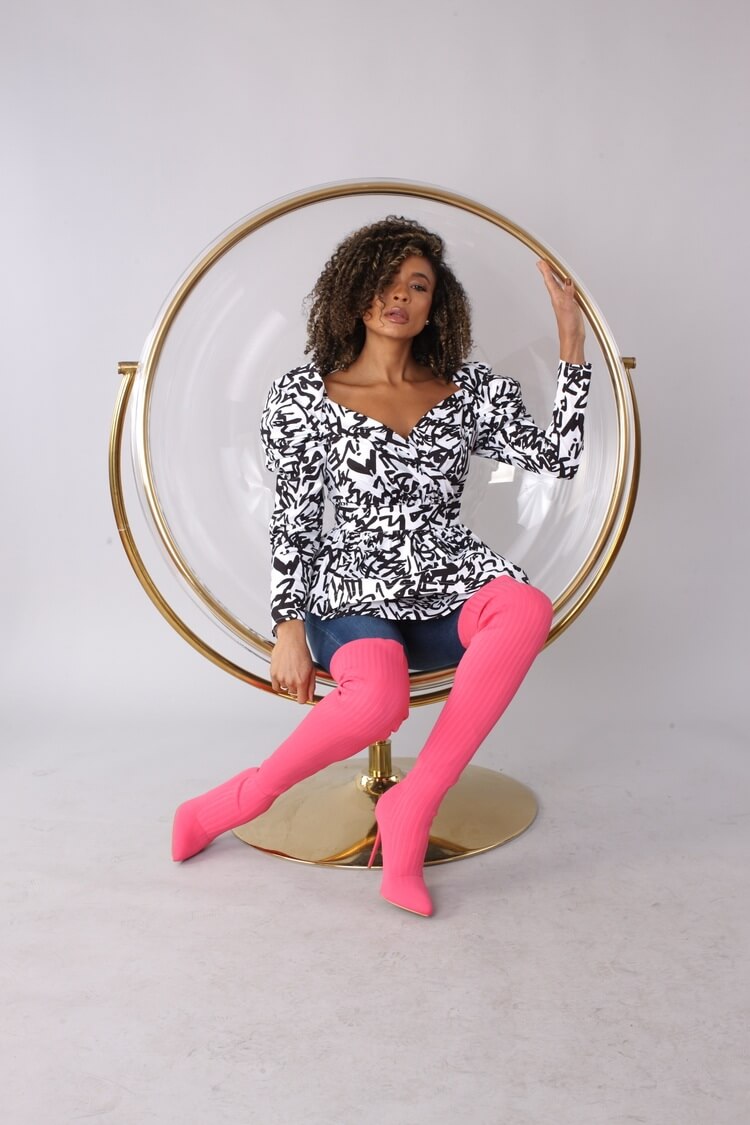 Angled sitting view of white and black puff sleeve wrap peplum top – For Her NYC