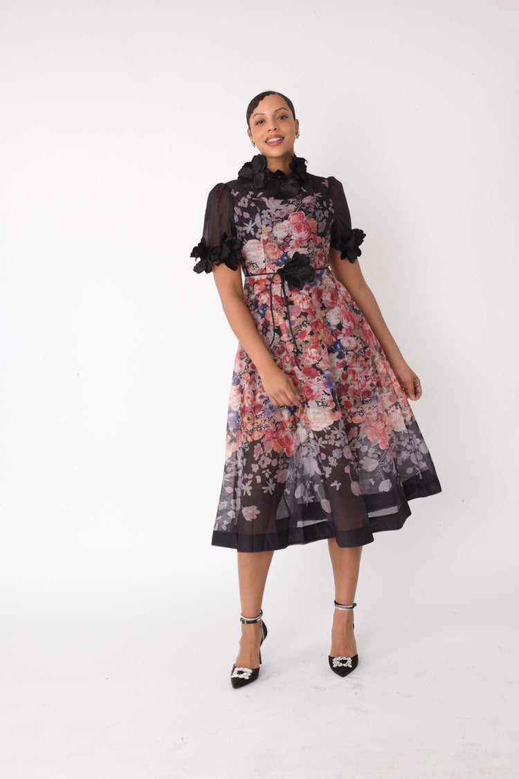 Model wearing the black multi romantic floral midi dress standing front facing, showcasing cascading floral print and sheer organza sleeve details by For Her NYC