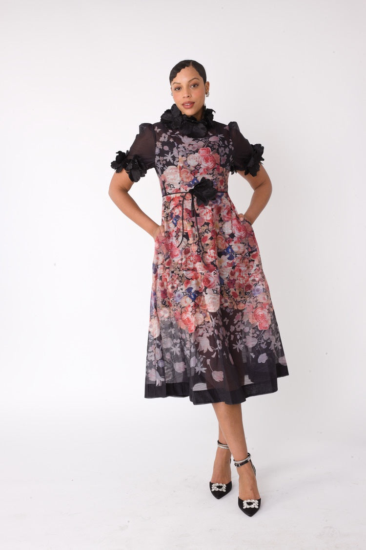 Model wearing the black multi romantic floral midi dress standing front facing, showcasing cascading floral print and sheer organza sleeve details by For Her NYC
