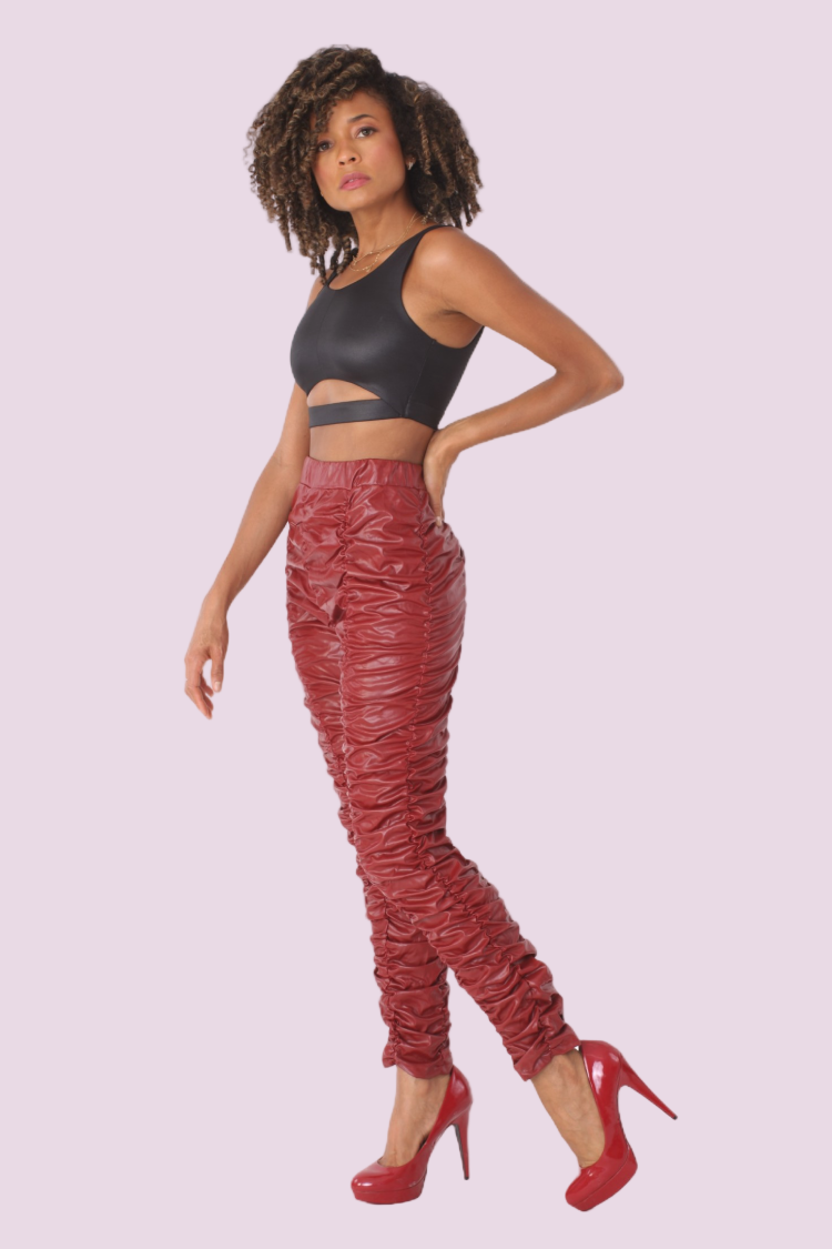 Front view of red ruched faux leather high-rise pants with figure-hugging fit styled with heels by For Her NYC