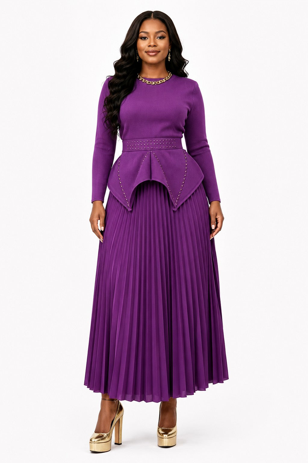 Model wearing the Purple Studded Peplum Pleated Skirt Set featuring a structured peplum top with subtle stud detailing, long sleeves, and a flowing pleated midi skirt by For Her NYC.