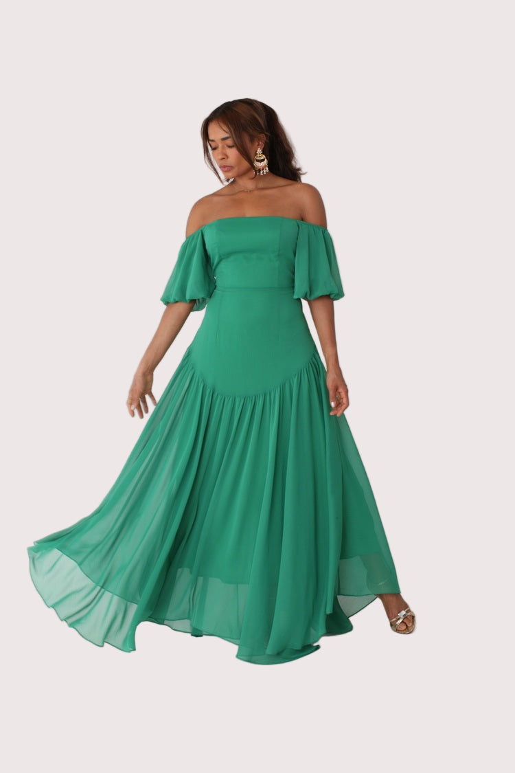 Emerald off-shoulder maxi dress shown on model walking forward with flowing movement, For Her NYC