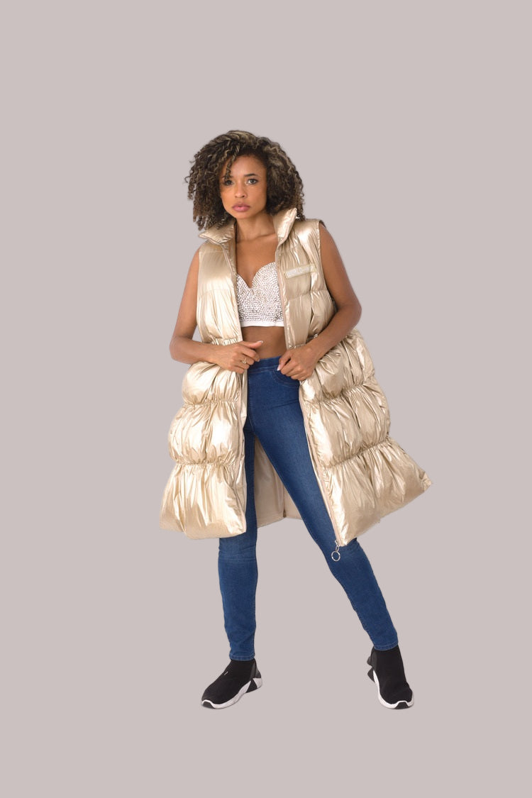Three-quarter view of nude tiered puffer vest layered over jeans — For Her NYC.