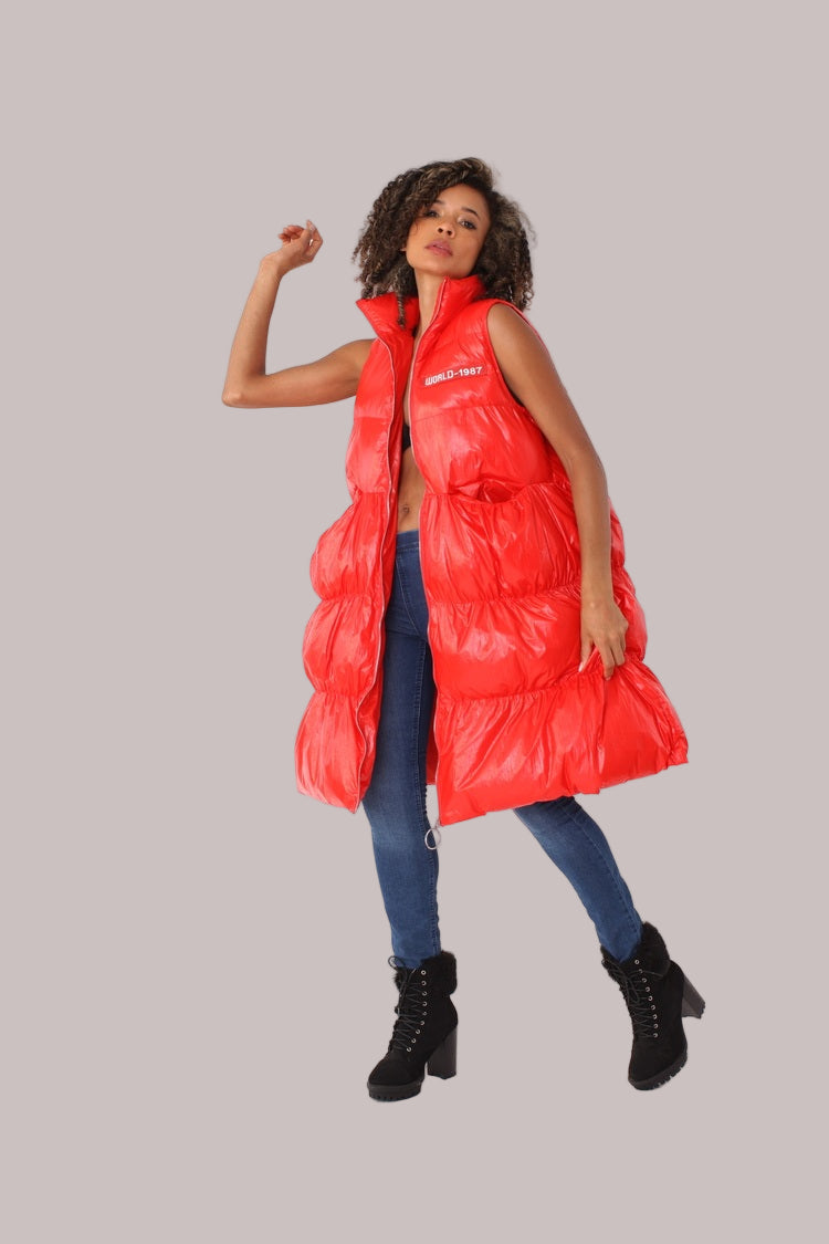 Three-quarter turn view of red tiered puffer vest with high collar — For Her NYC.