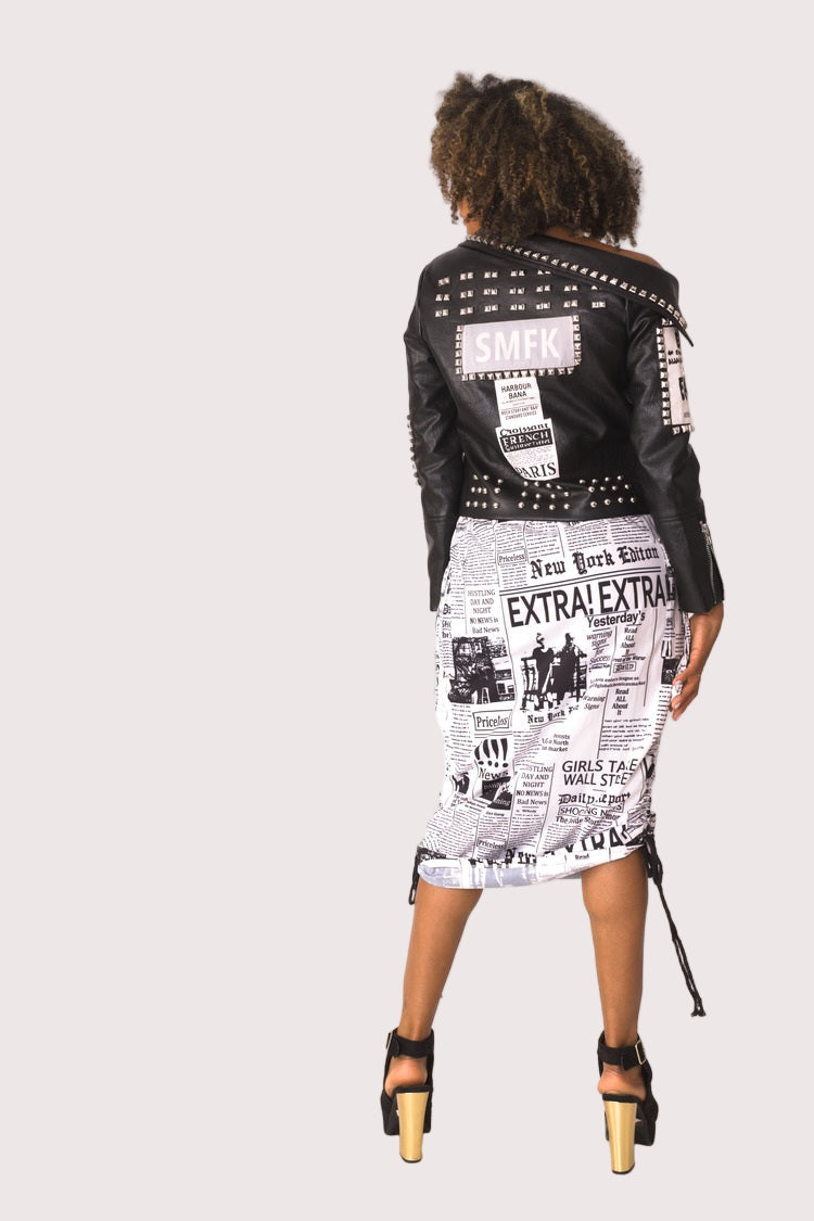 Back view of model wearing a newsprint woven midi skirt, showing the fitted shape and ruched waistband from behind, For Her NYC