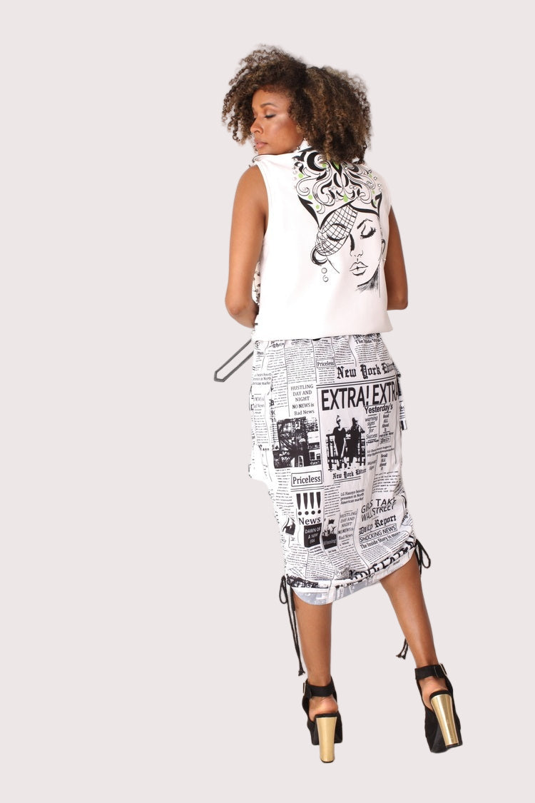 Back view of model wearing a newsprint woven midi skirt, showing the fitted shape and ruched waistband from behind, For Her NYC