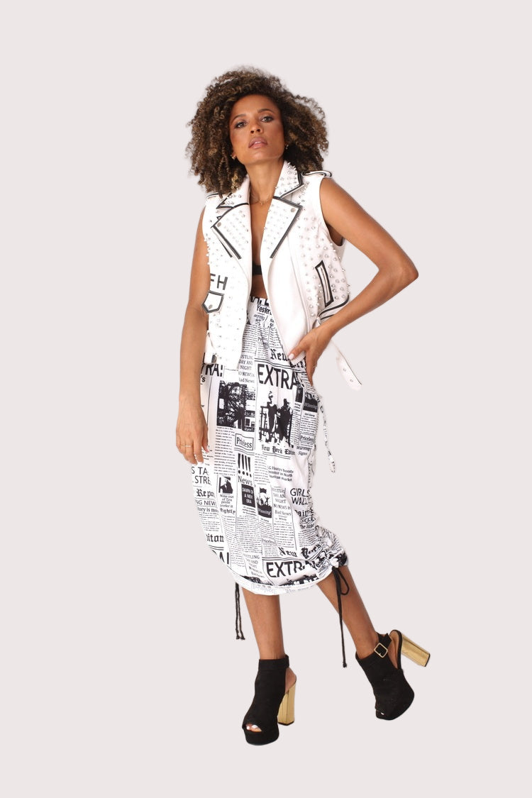 Model wearing a newsprint woven midi skirt in a front walking pose, showcasing the ruched waist and slim midi silhouette, For Her NYC